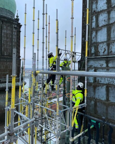 Ställningsbyggare klättrar i byggnadsställning på Högalidskyrkan.