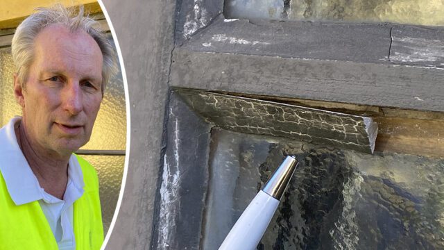 Jan-Åke Öberg står framför ett fönster och visar var det kan finnas asbest i fönsterkitt