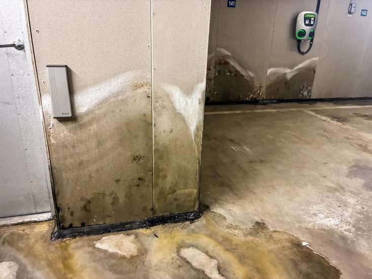 Vatten rinner över golvet och väggarna har tecken på fuktskador.