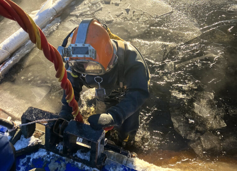Anläggningsdykaren Thomas Hedström på väg ner i vatten, täckt av isflak.