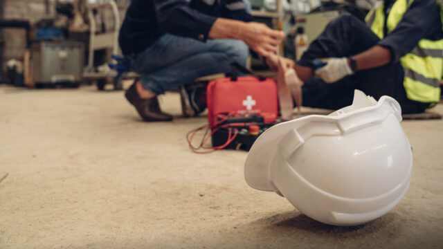 Genrebild på skadad arbetare som får första hjälpen.