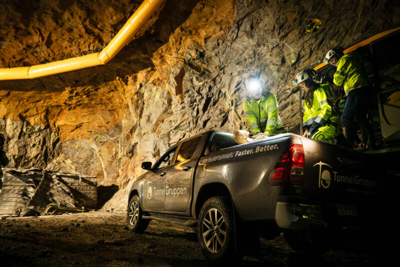 Arbetare ger första hjälpen på en docka, som ligger på flaket till en arbetsbil i tunneln.